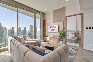A modern living room with a large sofa, a coffee table, and a TV mounted on the wall. - Free Housekeeping Visits During Your Stay - Stayshort - 1 BR in Business Bay Sleeps 4 With Burj Views (Dubai)