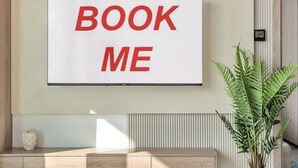 Een aan de muur bevestigde televisie met de tekst 'BOOK ME' in rode letters.