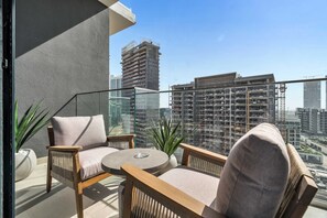 Ein Balkon mit Blick auf hohe Gebäude, einem runden Tisch und zwei Stühlen.