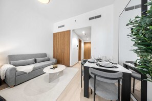 Ein modernes Wohnzimmer mit grauem Sofa, einem Couchtisch und einem Essbereich mit Tisch für vier Personen.