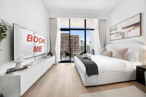 Ein modernes Schlafzimmer mit einem großen Bett, einem Fernseher und Blick auf die Stadt.