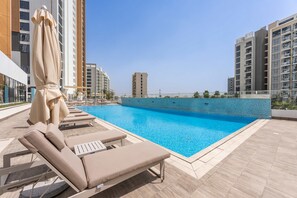 A rooftop pool with lounge chairs and umbrellas, surrounded by modern buildings. - Free Housekeeping Visits During Your Stay - Stayshort - Modern Studio That Sleeps 4 at Riviera Beachfront (Dubai)