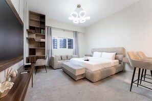 Ein modernes Hotelzimmer mit einem großen Bett, einer Couch, einem Schreibtisch und einem Fernseher.