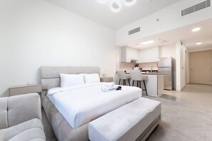 Ein modernes Hotelzimmer mit einem großen Bett, einer kleinen Küchenzeile und einem separaten Essbereich.