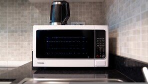 Eine Toshiba-Mikrowelle steht auf einer Küchenarbeitsplatte mit einer gefliesten Rückwand.