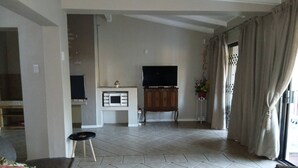 Una sala de estar con un sofá, una televisión, un mueble y una planta en maceta.