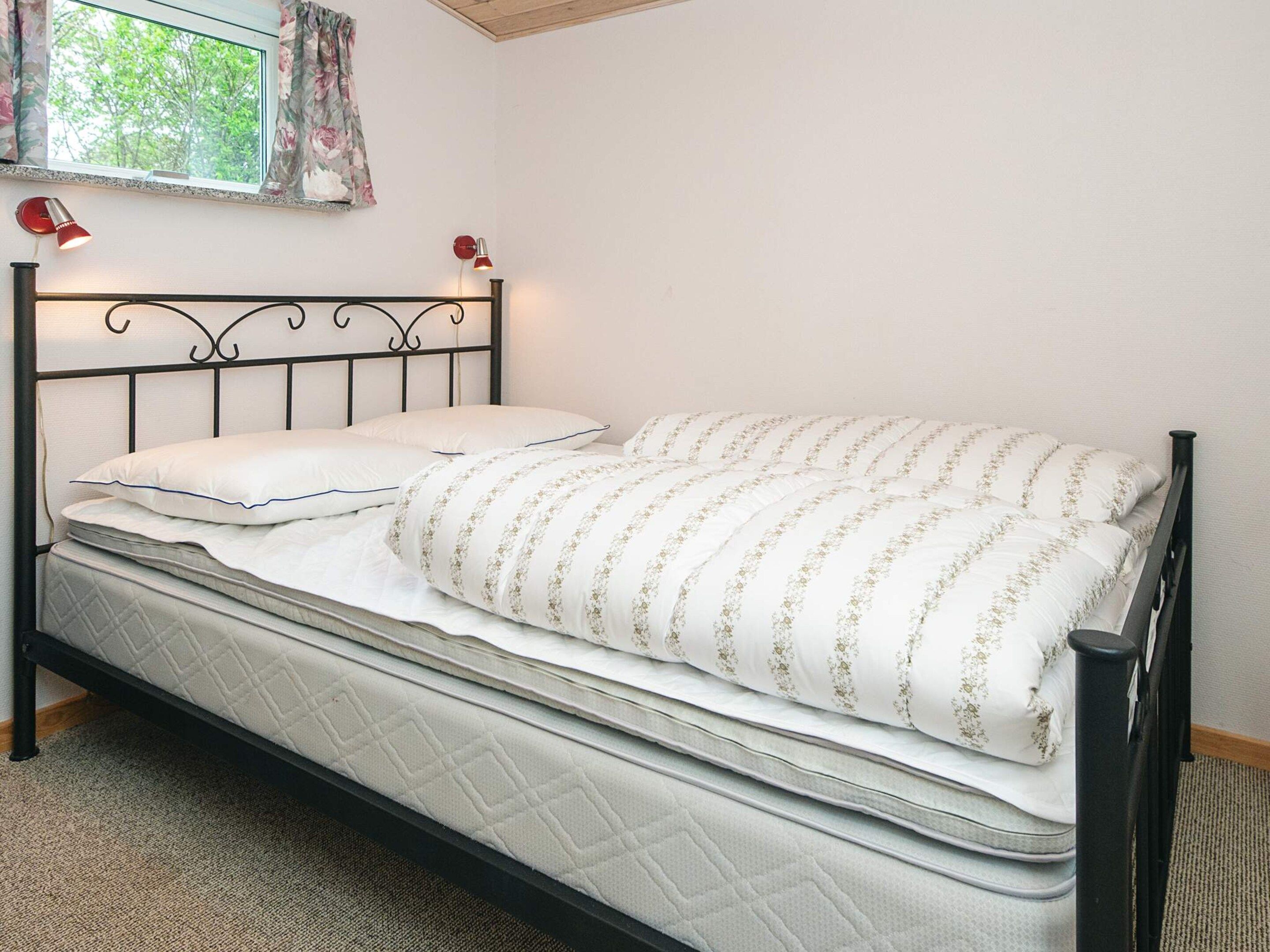 A single bed with a metal frame, white bedding, and two bedside lamps.