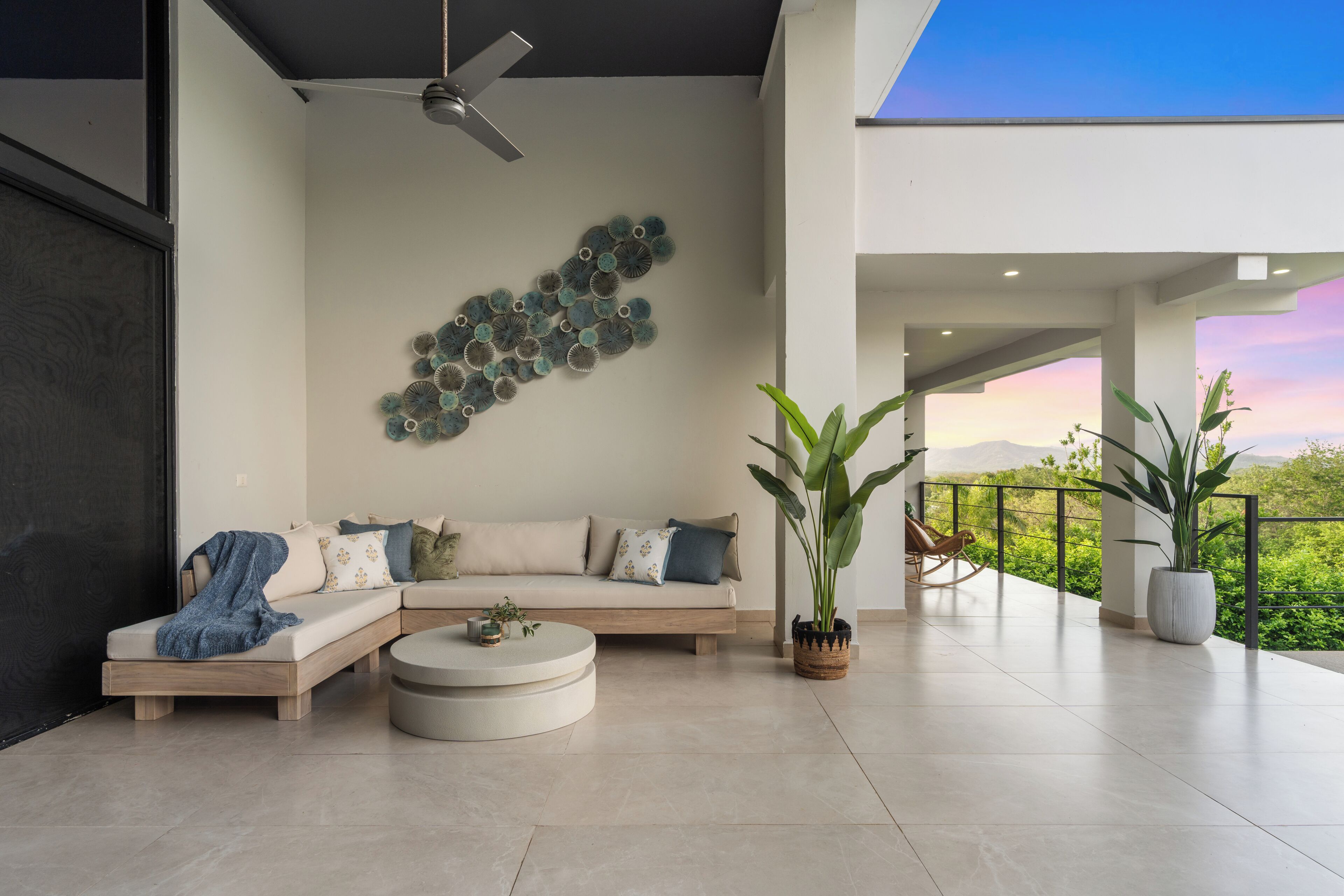 A modern living room with a sectional sofa, a round coffee table, and a ceiling fan.