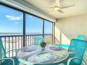 A balcony with a glass table, chairs, and a decorative bowl.