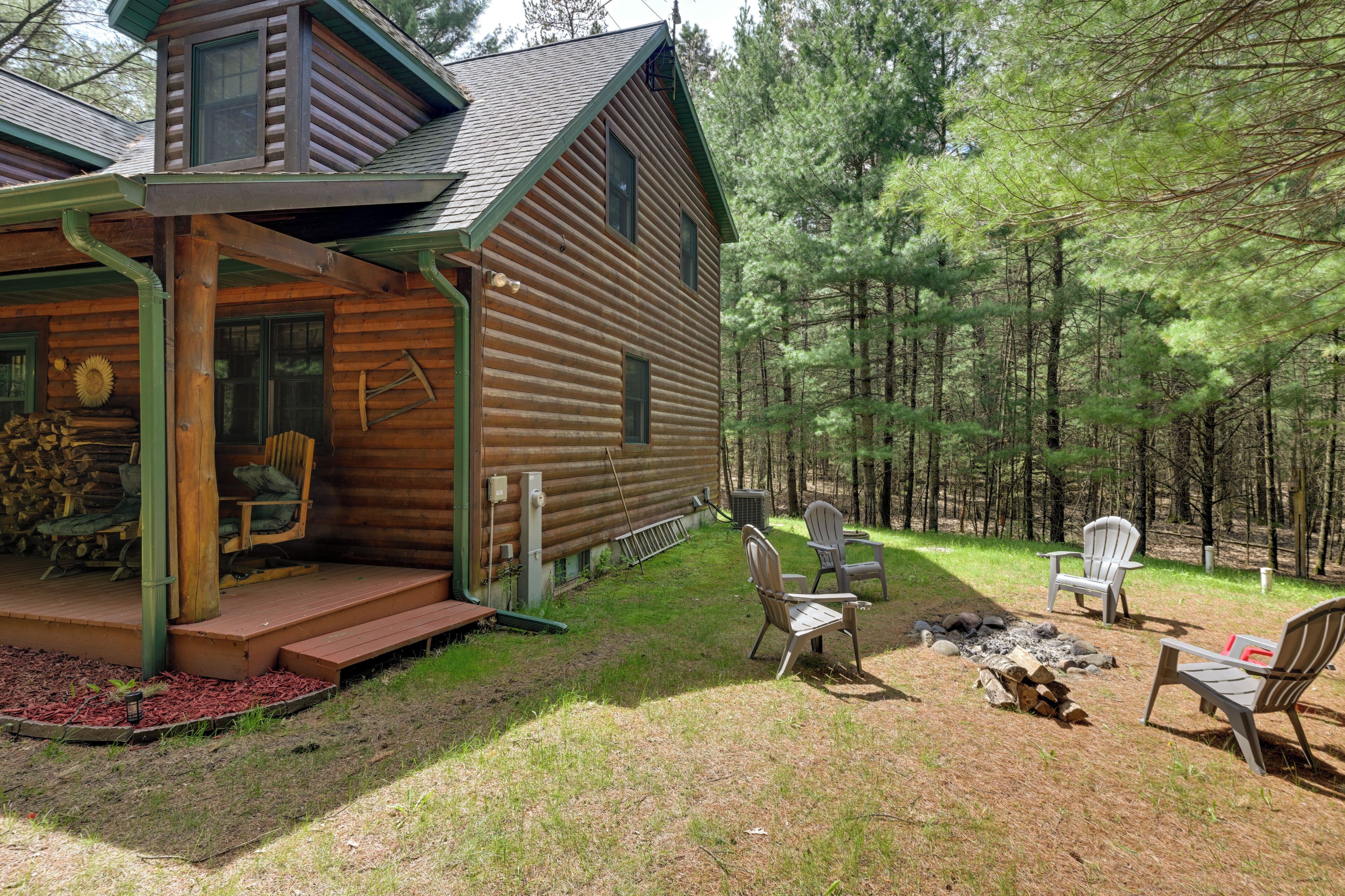 A log cabin with a porch, outdoor seating, and a fire pit.