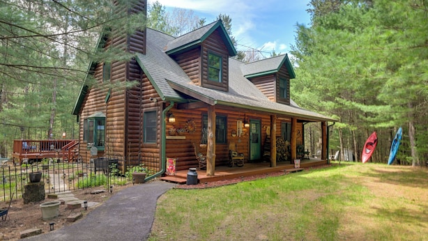 A log cabin with a porch, a covered deck, and a kayak.