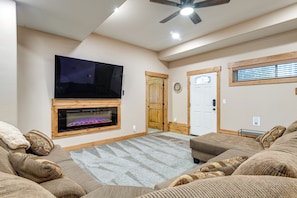 Una sala de estar con chimenea, televisor y ventilador de techo.