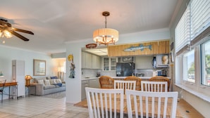 A spacious living area with a dining table, chairs, and a kitchen in the background. - Bayfront Madeira Beach Retreat Pool, Sun & Sand (Madeira Beach)