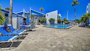 A pool area with lounge chairs, a swimming pool, palm trees, and modern buildings. - Bayfront Madeira Beach Retreat Pool, Sun & Sand (Madeira Beach)