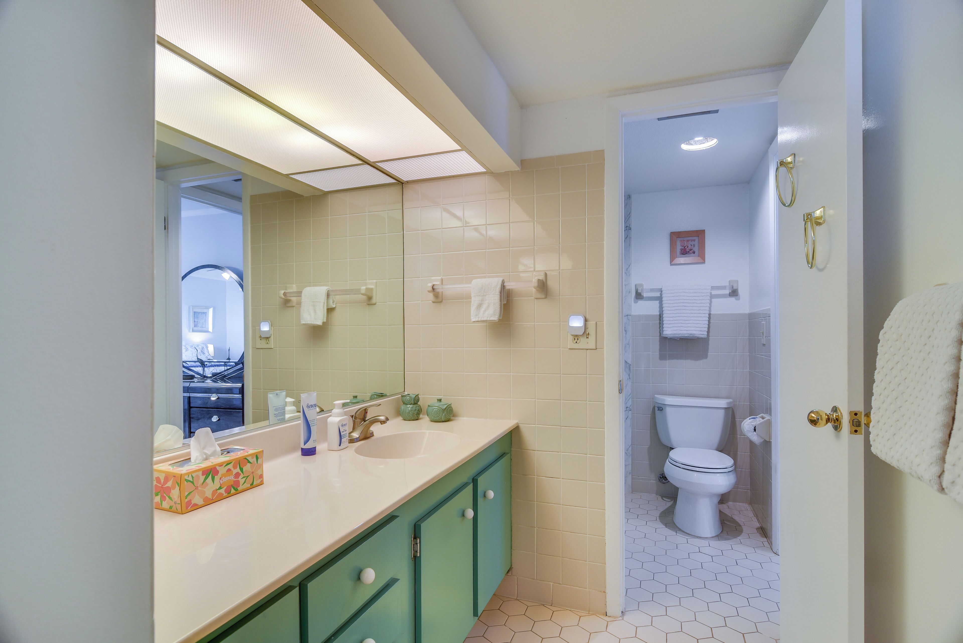Un baño con lavamanos, espejo e inodoro.