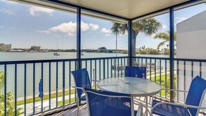 A balcony with a view of a body of water, a table, and chairs. - Bayfront Madeira Beach Retreat Pool, Sun & Sand (Madeira Beach)