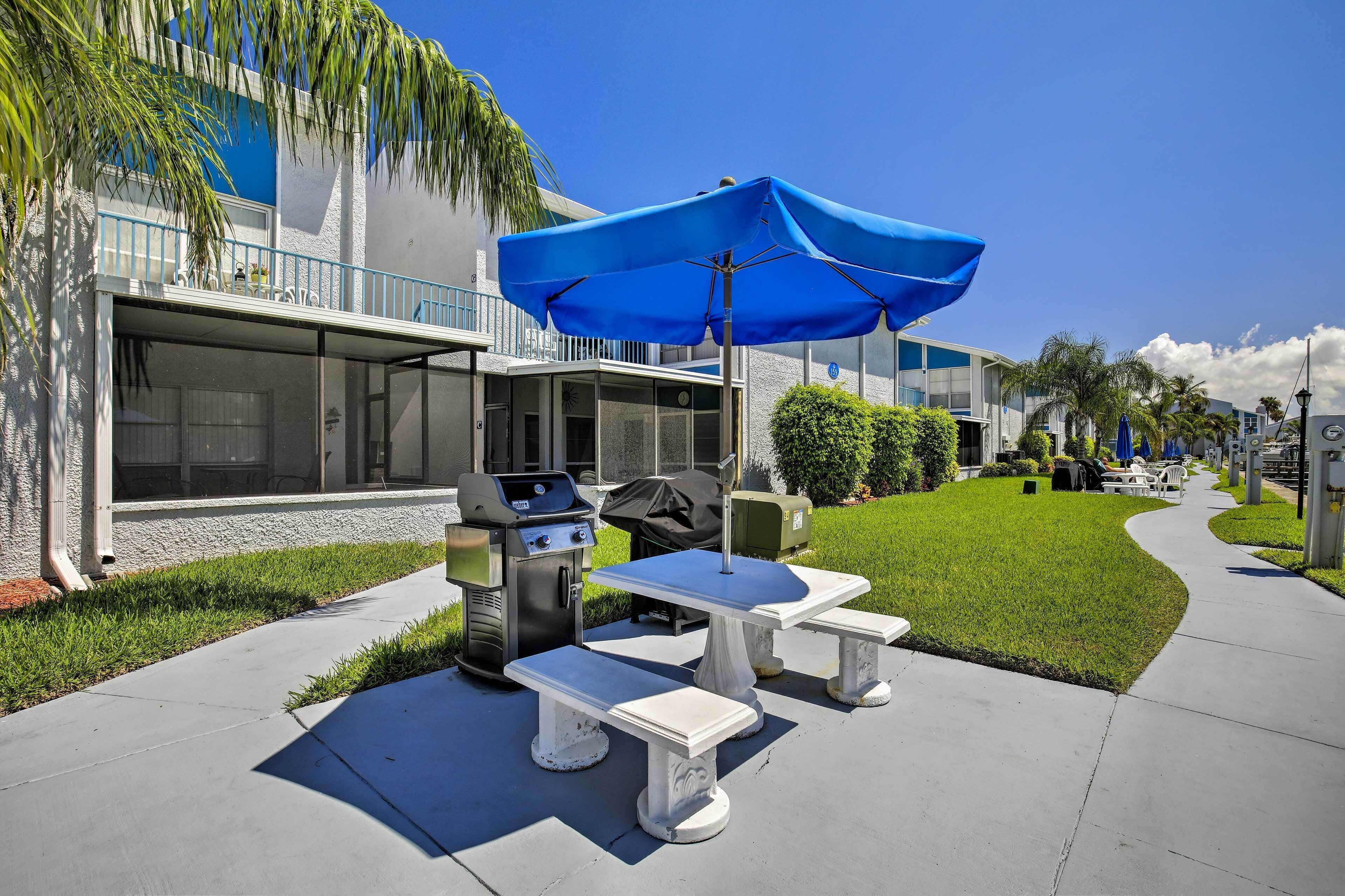 A patio with outdoor furniture, a grill, and a blue umbrella.