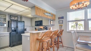 A kitchen with a black refrigerator, white cabinets, a microwave, and a wooden island with bar stools. - Bayfront Madeira Beach Retreat Pool, Sun & Sand (Madeira Beach)