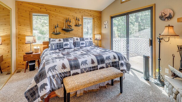 A bedroom with a large bed, wooden walls, a bench, a desk, and a window. - Alpine Luxury & Mtn Views: Family Big Bear Escape! (Big Bear Lake)