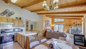 A spacious kitchen with wooden cabinets, a central island, and a dining area with a large wooden table. - Alpine Luxury & Mtn Views: Family Big Bear Escape! (Big Bear Lake)