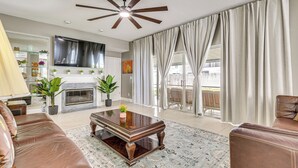 A living room with a fireplace, leather sofas, a coffee table, and a ceiling fan. - Screened Lanai & Yard! Family Getaway in Apopka (Apopka)