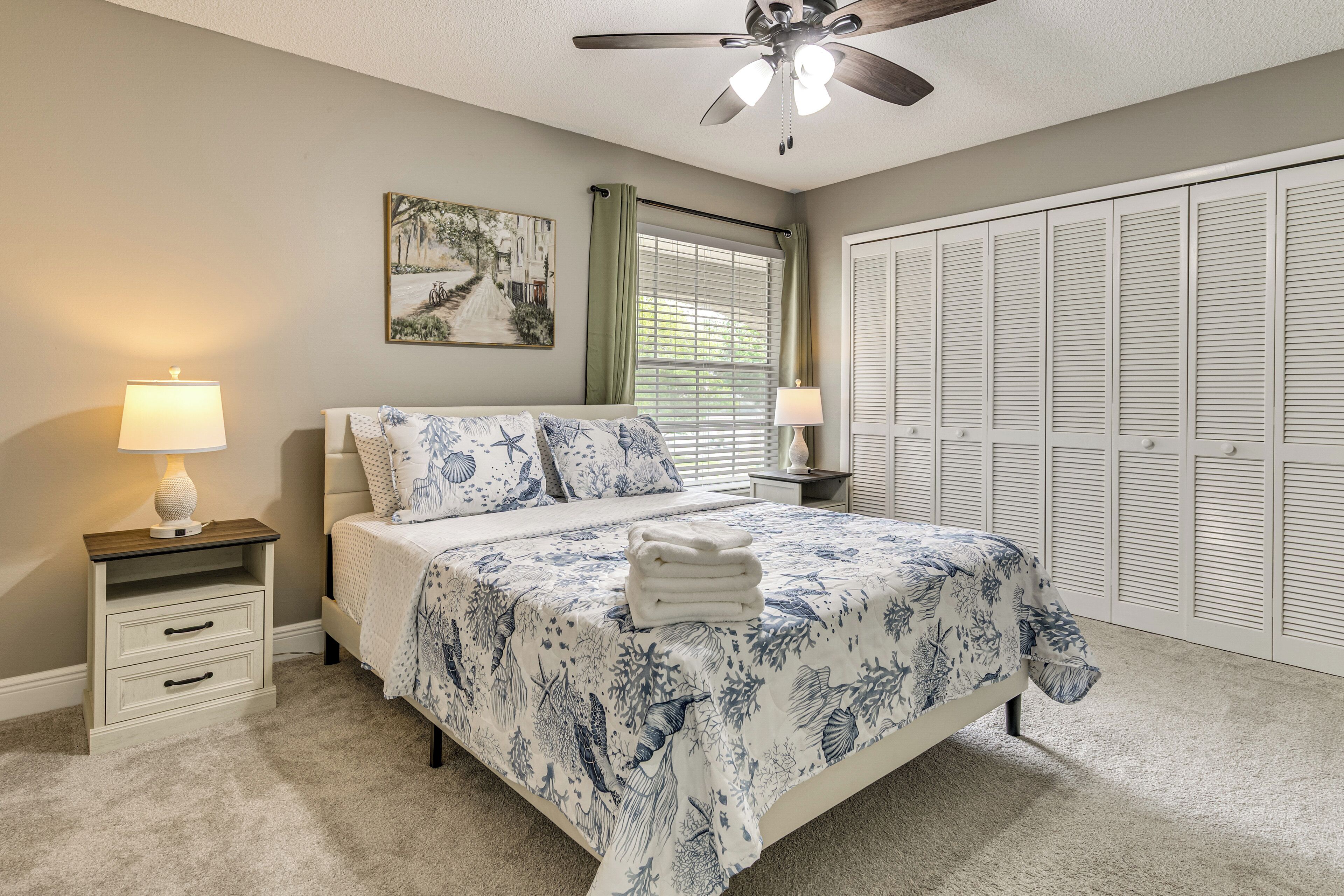 A bedroom with a bed, nightstands, a ceiling fan, a window with blinds, and a closet.