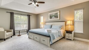A bedroom with a bed, a chair, a bedside table, a lamp, a ceiling fan, and a window with blinds. - Screened Lanai & Yard! Family Getaway in Apopka (Apopka)