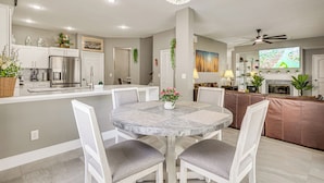 A modern kitchen with a dining area, a chandelier, and a flat-screen TV. - Screened Lanai & Yard! Family Getaway in Apopka (Apopka)