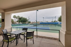 An outdoor tennis court with a seating area featuring chairs and a table. - Golf, Swim, Play & Relax! Gated Sun Lakes Home (Chandler)