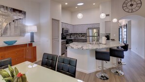 A modern kitchen with a marble island, pendant lighting, and a clock on the wall. - Golf, Swim, Play & Relax! Gated Sun Lakes Home (Chandler)