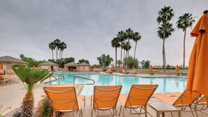 A pool area with lounge chairs and umbrellas, surrounded by palm trees and buildings. - Golf, Swim, Play & Relax! Gated Sun Lakes Home (Chandler)