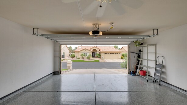 A garage with a ceiling fan, a projector, and a garage door. - Golf, Swim, Play & Relax! Gated Sun Lakes Home (Chandler)
