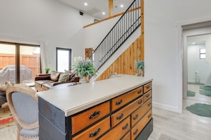 Un vaste espace de vie agrémenté d’un escalier en bois, d’une grande armoire en bois dotée de nombreux tiroirs, d’un canapé et d’une table à manger.