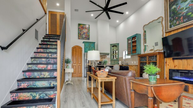 A staircase with floral patterns, a wooden table with a basket, a brown leather sofa, and a television. - 2 Mi to St Lucie Access! Stuart Getaway w/ Patio (Stuart)