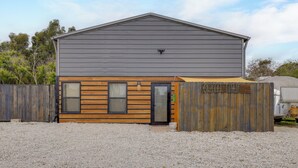 A two-story building with a grey upper level and a wooden lower level, featuring a door and windows. - 2 Mi to St Lucie Access! Stuart Getaway w/ Patio (Stuart)