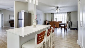 A modern kitchen with a central island, a dining area with a table and chairs, and a ceiling fan.