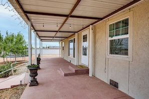 A covered outdoor area with steps leading to a door, potted plants, and a view of the surrounding area. - Family Friendly! Rural El Paso Home: Patio & Grill (El Paso)