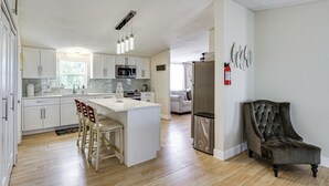 A modern kitchen with white cabinetry, a central island with bar stools, a built-in microwave, and a refrigerator. - Family Friendly! Rural El Paso Home: Patio & Grill (El Paso)