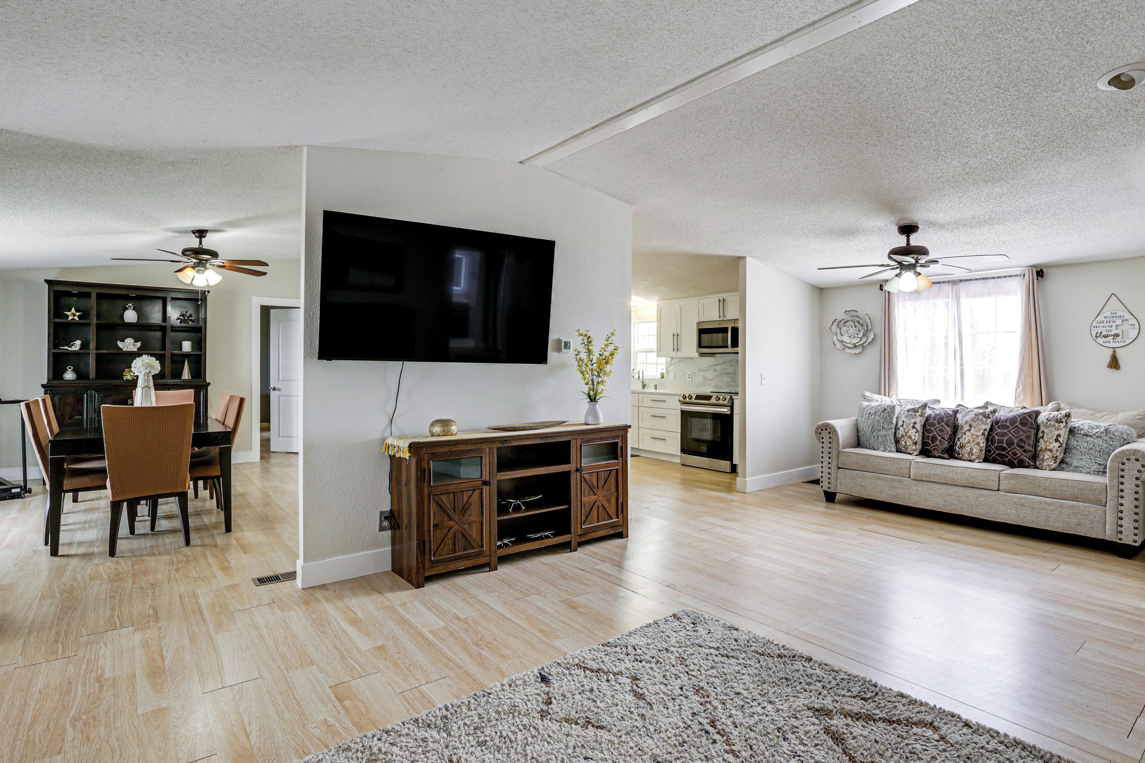 A spacious living area with a flat-screen TV, wooden entertainment center, dining table, and sofa.