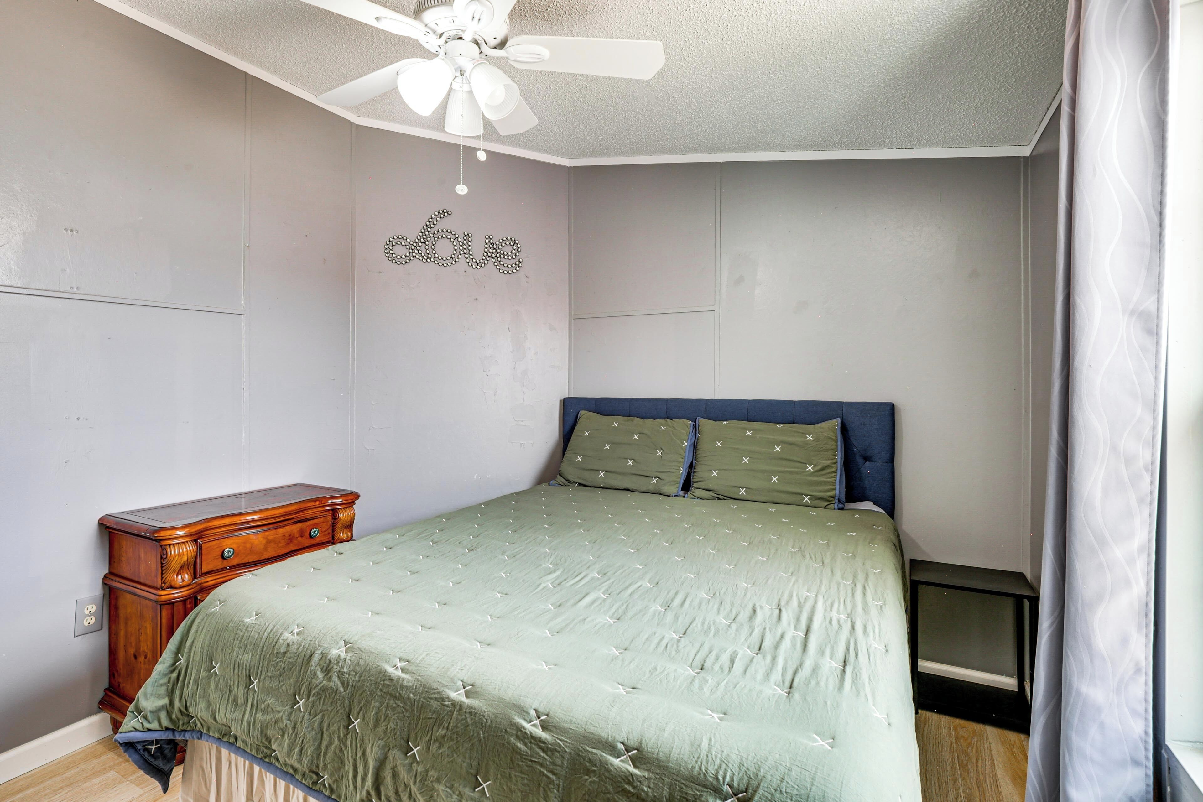 Ein Schlafzimmer mit Bett, Kommode, Deckenventilator und Wanddekoration.