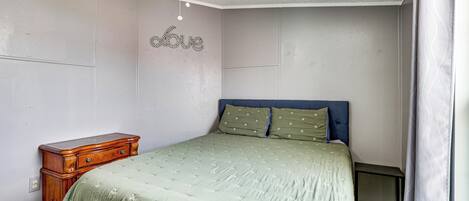 Ein Schlafzimmer mit Bett, Kommode, Deckenventilator und Wanddekoration.