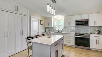 A modern kitchen with white cabinetry, a central island, stainless steel appliances, and pendant lighting.