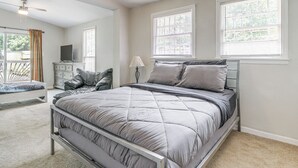 A bedroom with a bed, a dresser, a TV, and a window.