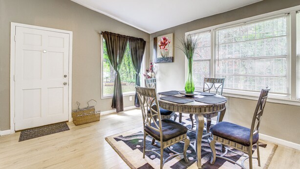 A dining area with a round table, chairs, a vase, and a door.
