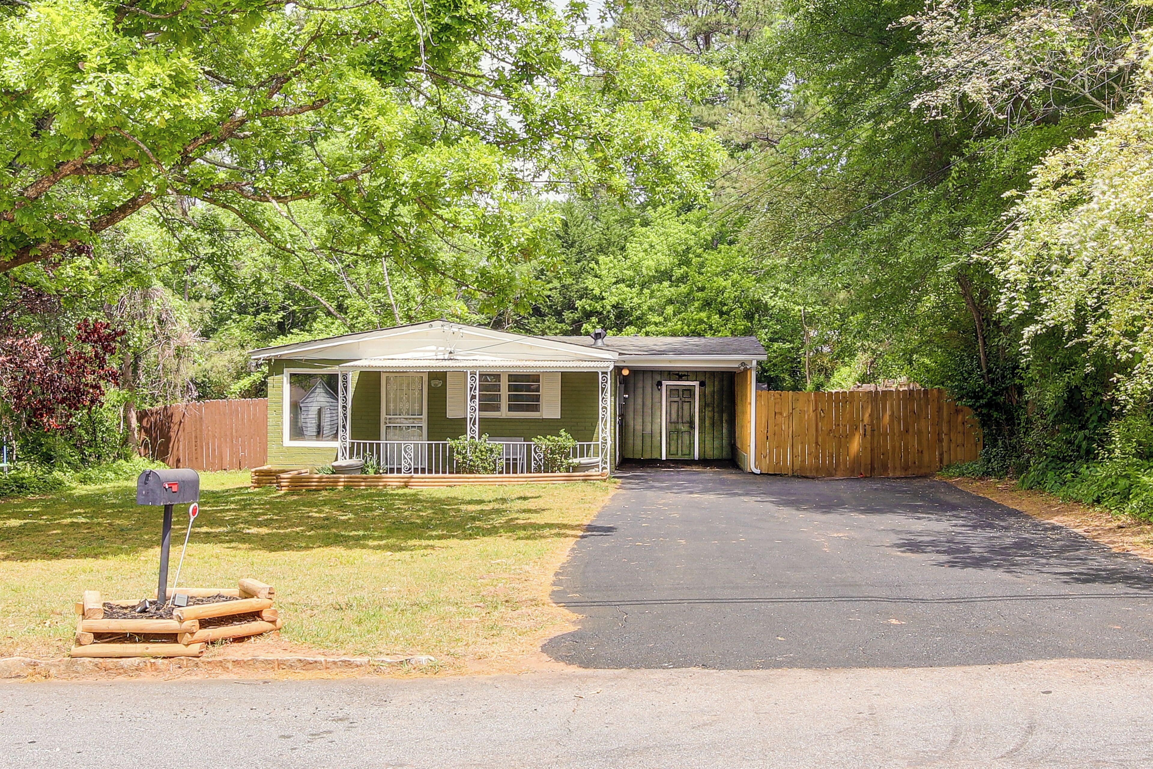A single-story house with a front porch, a driveway, and a wooden fence.