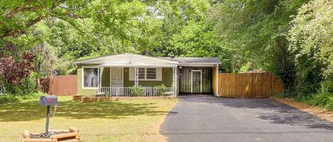 A single-story house with a front porch, a driveway, and a wooden fence.
