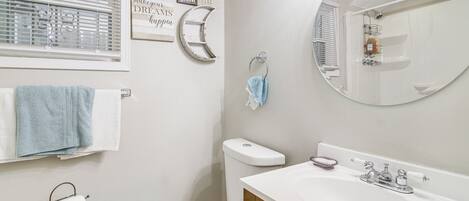 A bathroom with a toilet, sink, mirror, towel rack, and motivational wall art.