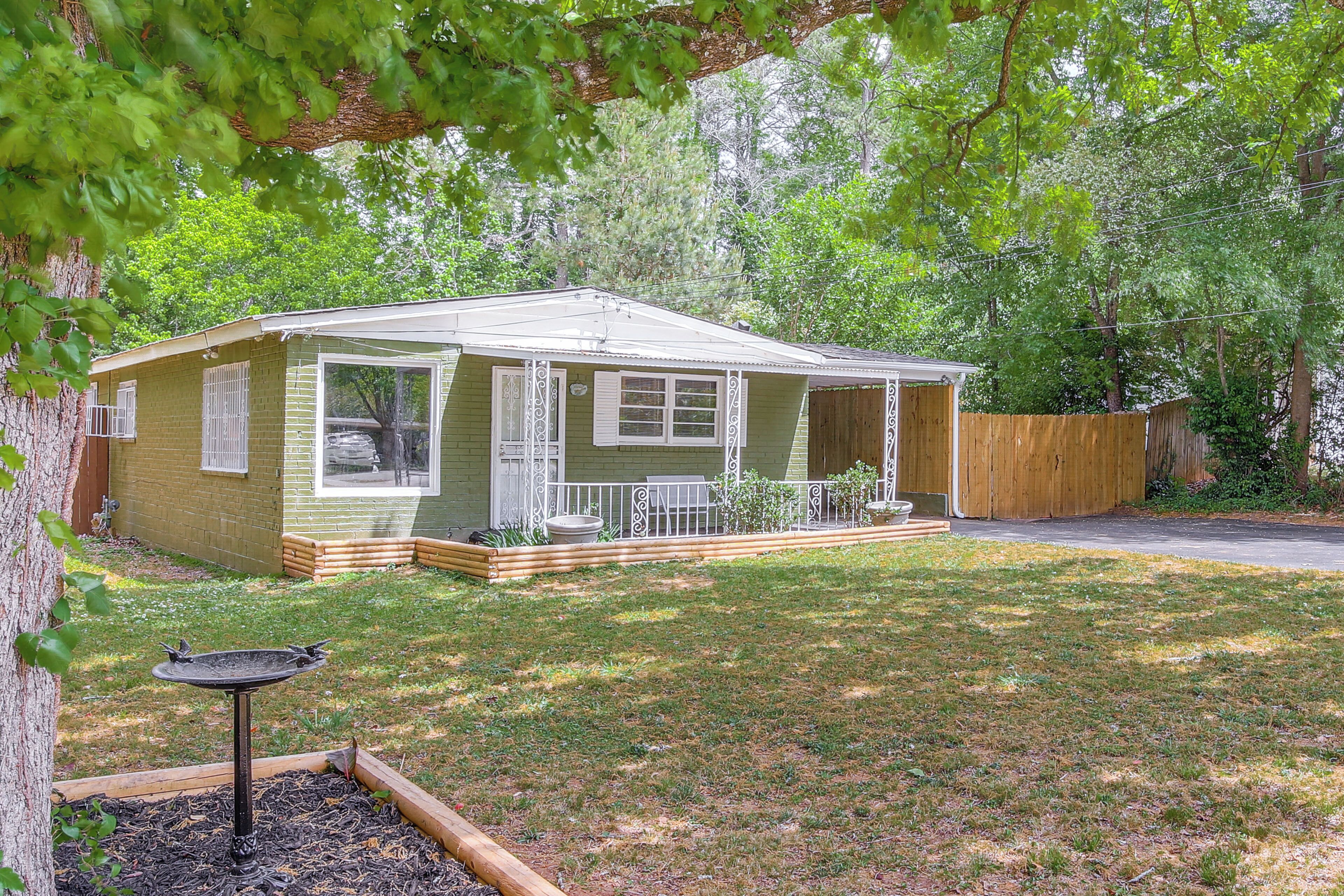 A single-story house with a front porch, a small deck, and a fenced backyard.