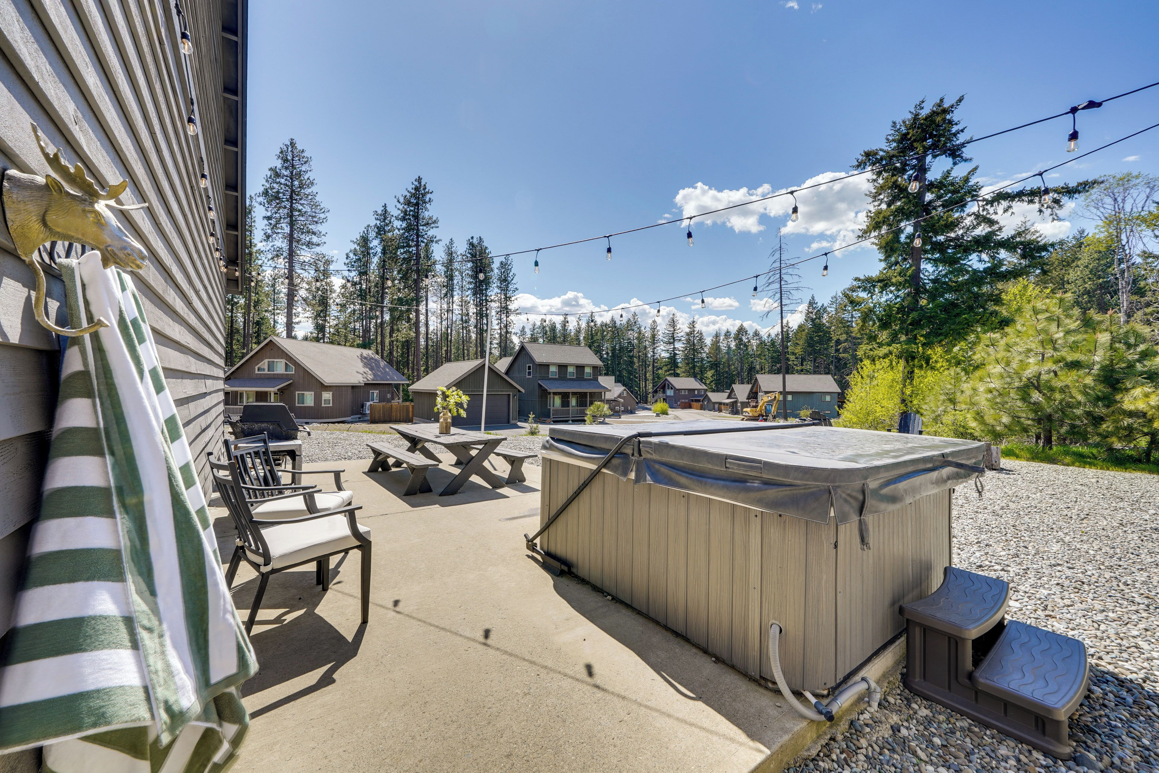 A patio area with outdoor seating, a hot tub, and a view of a forested area.