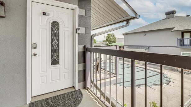 A residential building with a white door, a balcony with a metal railing, and a view of a parking lot. - Walkable Retreat Near The Island! Gateway to Gsmnp (Pigeon Forge)